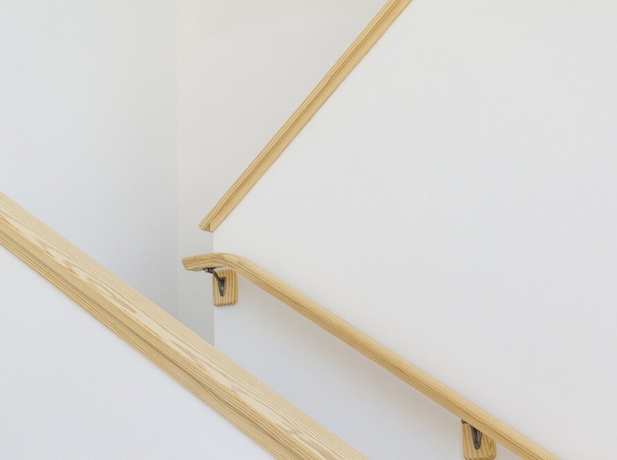 A photo of a wooden hand rail next to stairs.